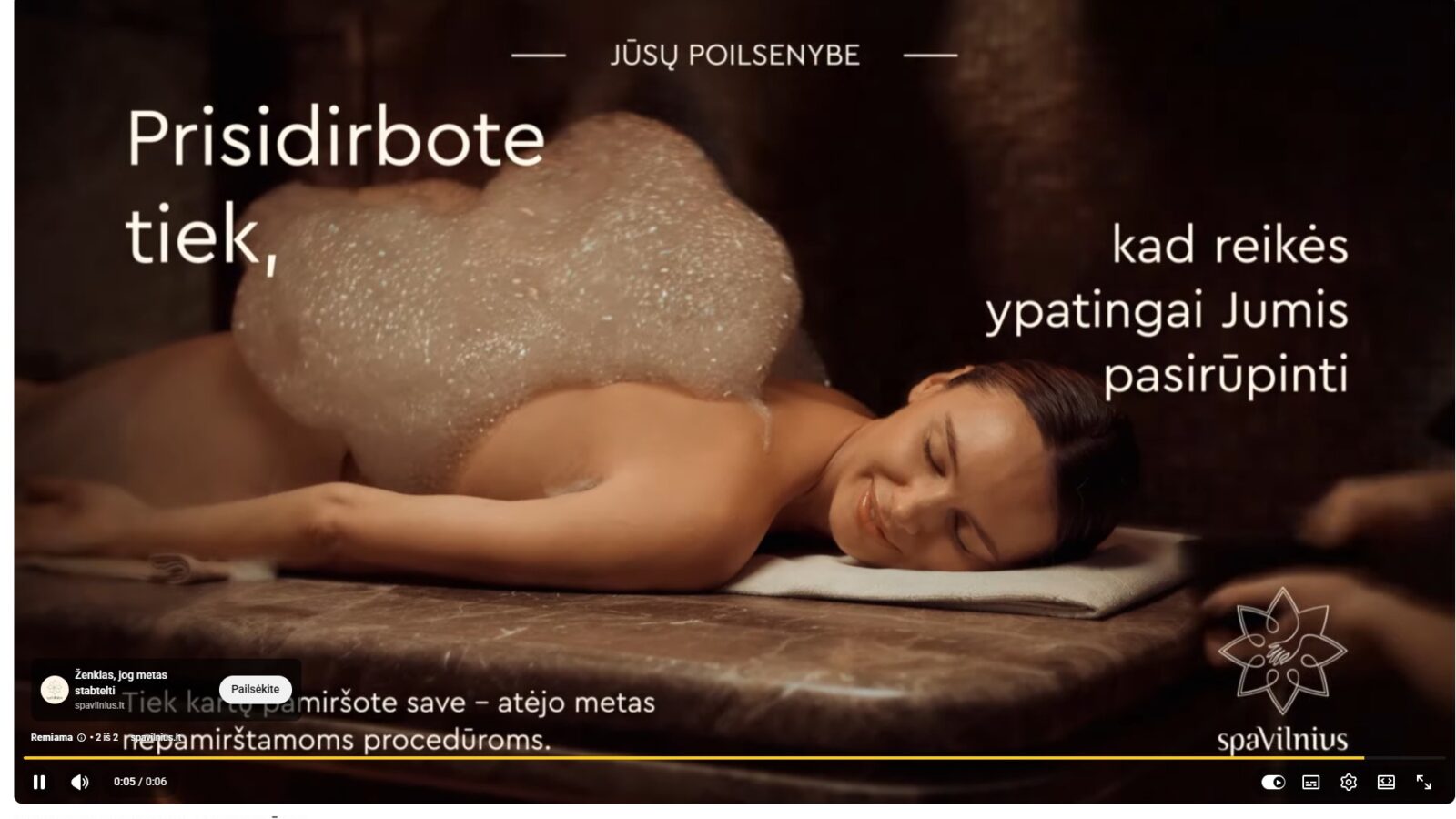 Moteris guli ant masažo stalo SPA aplinkoje, jos nugara padengta putomis, ji atsipalaidavusi ir šypsosi, perteikiant poilsio ir geros savijautos akimirką.